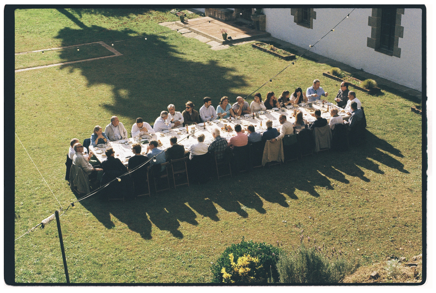 Personas compartiendo una mesa durante un evento, fotografía analógica